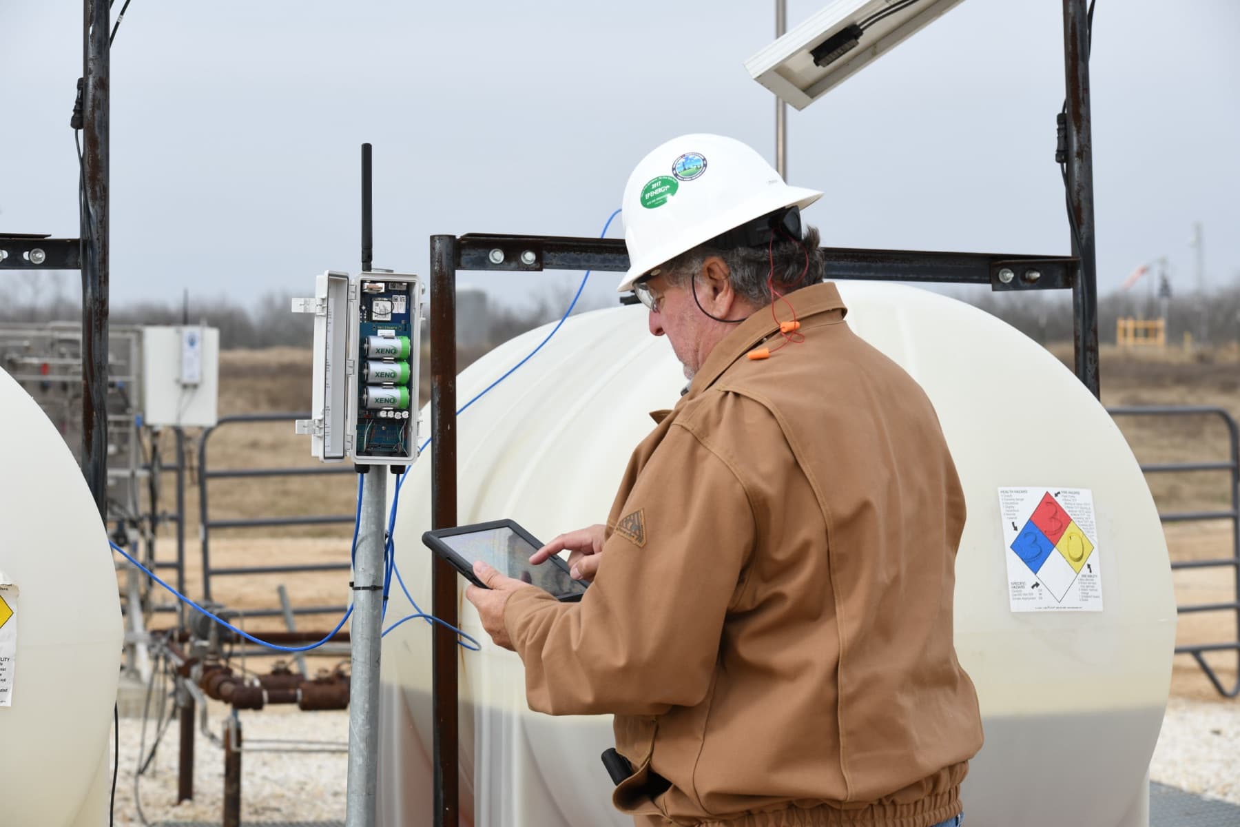 WellAware team member reviewing field data on an iPad at a tank site.