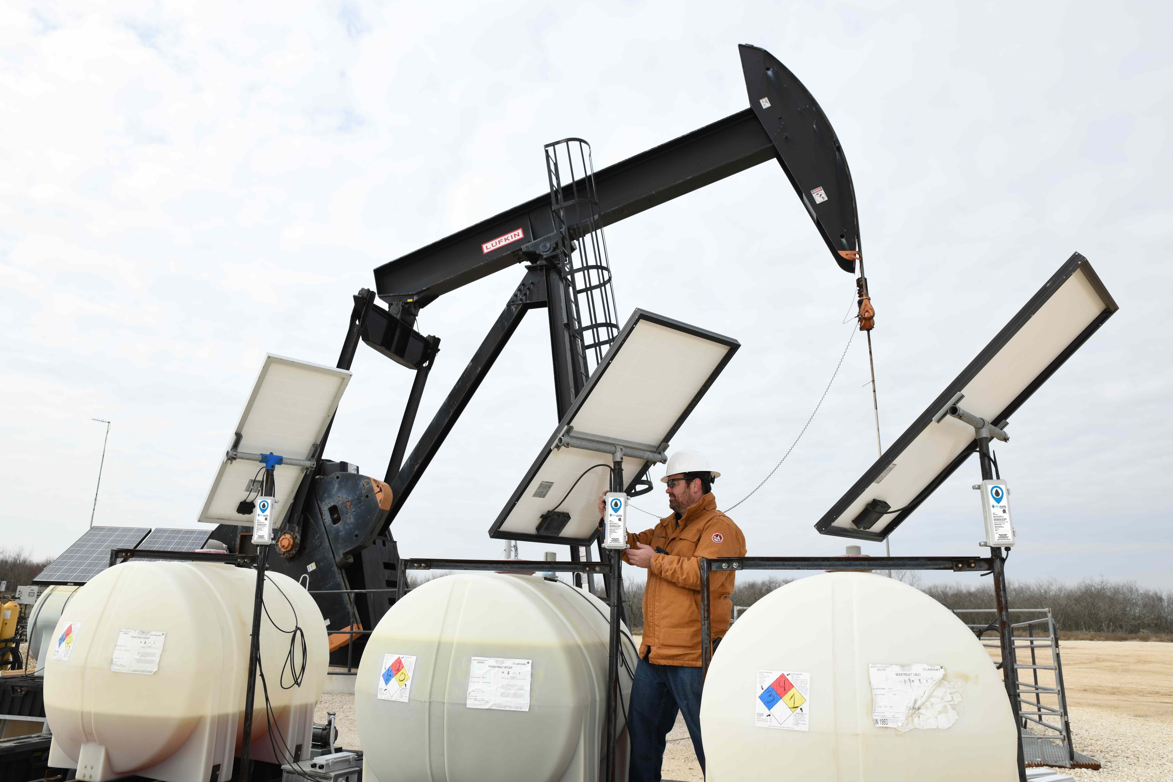WellAware WIRC sensors installed on three chemical tanks with solar panels at an oilfield site