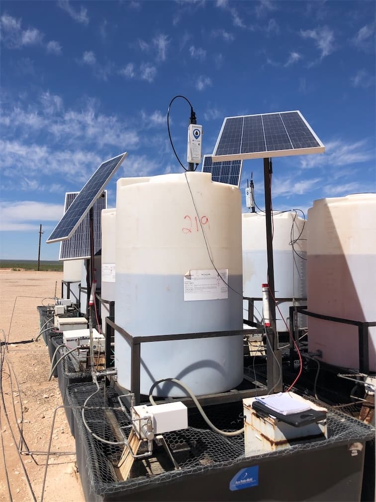 Multiple chemical tanks with WellAware sensors and solar panels at oilfield site