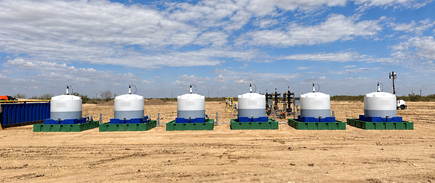 Row of WellAware-monitored chemical injection tanks on skids at an oilfield site